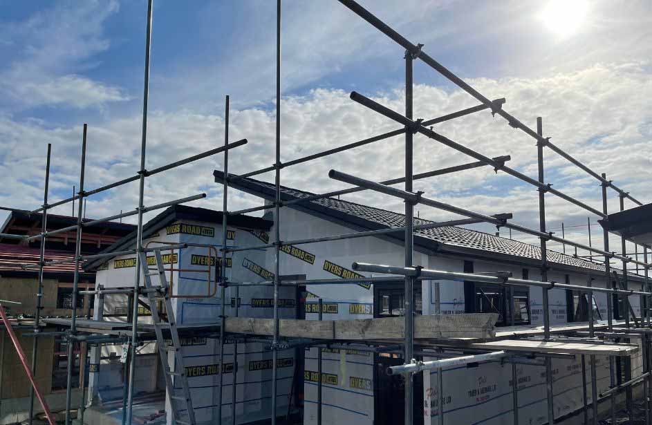 Commercial roofing installation on Auckland building with scaffolding and long-run steel roofing system
